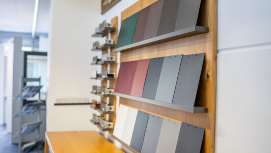 Auswahlwand im Showroom von Fensterbau Knipping mit Farbmustern und Profilschnitten für Fenster- und Türrahmen in verschiedenen Ausführungen.