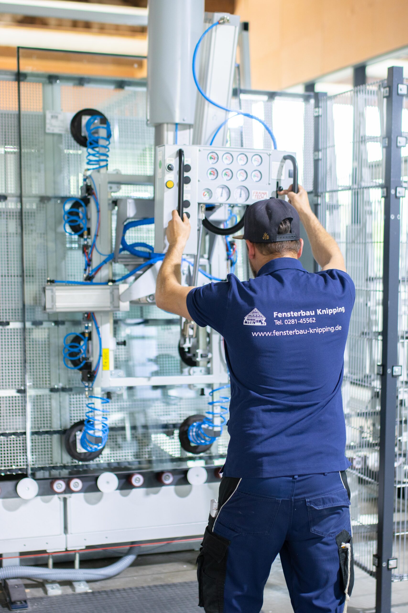 Mitarbeiter von Fensterbau Knipping bedient eine automatisierte Maschine zur Glasverarbeitung in der Produktionshalle.